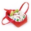 Petit couffin en tissu rouge avec édredon blanc avec motif rouge et vert et dedans une petite poupée en tissu au bonnet pointu rouge