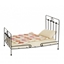 Poppenbed in zwart gelakt metaal in traditionele stijl met matras, hoofdkussen en patchwork dekentje.