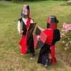 Deux enfants jouent au chevalier normand dans un jardin.