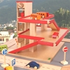 Parking garage jouet avec ascenseur de couleur bois naturel avec accents rouges, peuplé de petites voitures en bois.